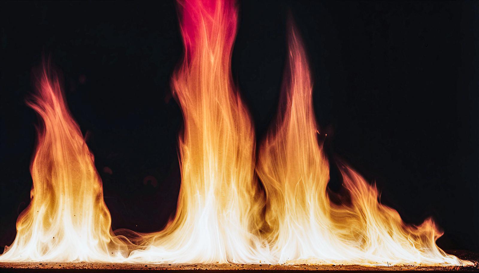 Multiple flames erupting from a black background, transitioning in color from white to red.