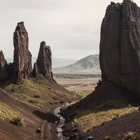 柱状節理の岩峰が立ち並ぶ火山地帯風の大地と渓流の写真