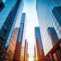見上げたガラス張りの高層ビル群の写真