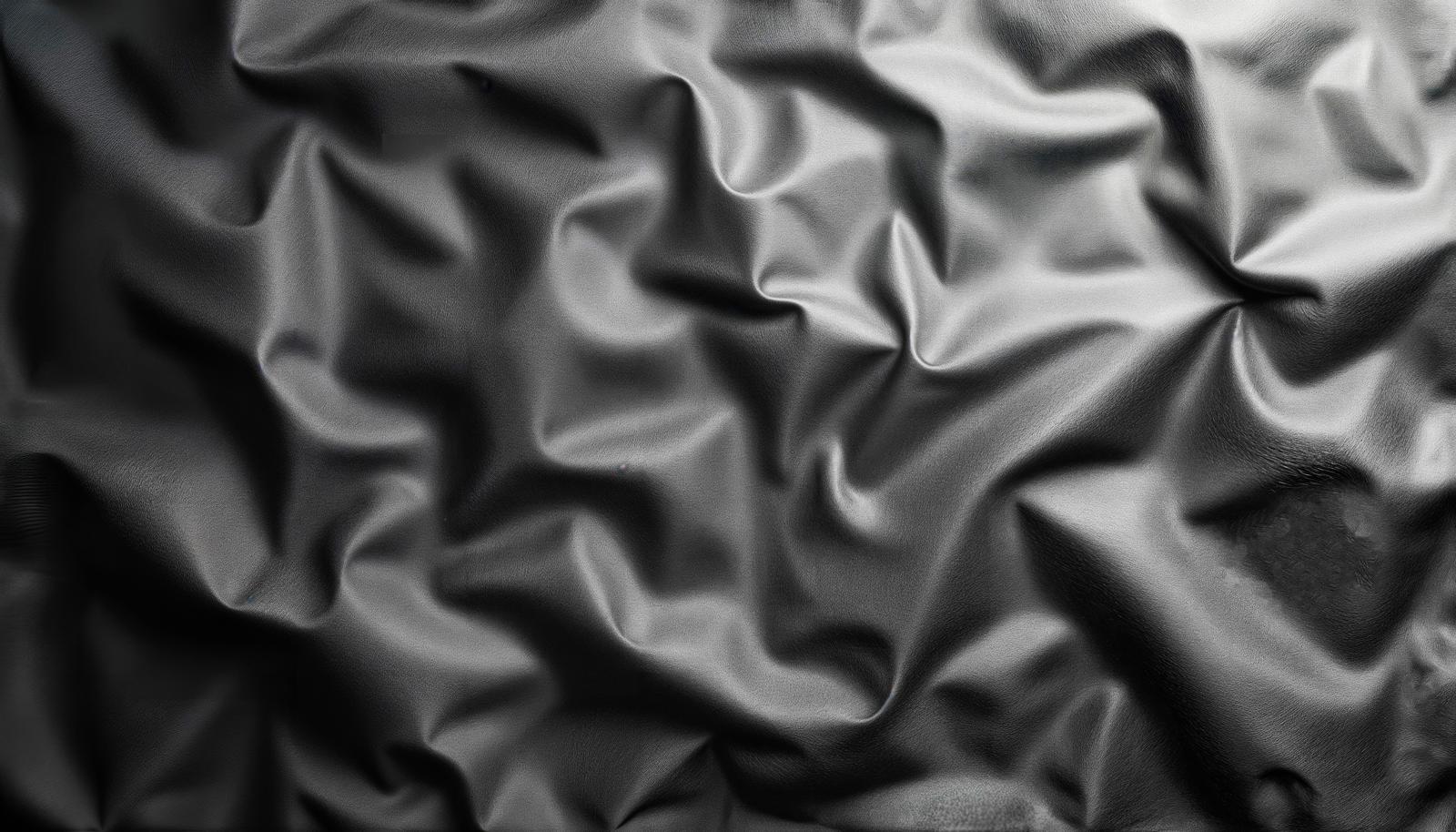 くしゃくしゃに丸めた黒いビニール素材の表面に光が当たりシワや折り目が浮かぶテクスチャー