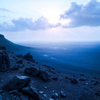 夜明けの光が差す荒々しい海岸のAI画像
