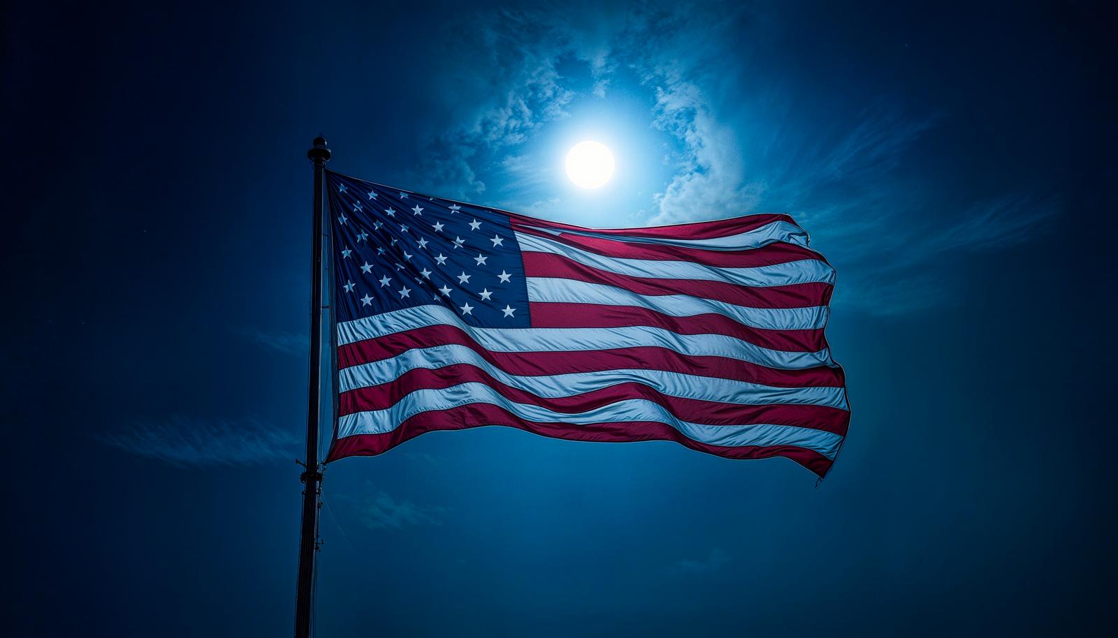 月明かりの夜空を背景に風になびくアメリカ合衆国の国旗