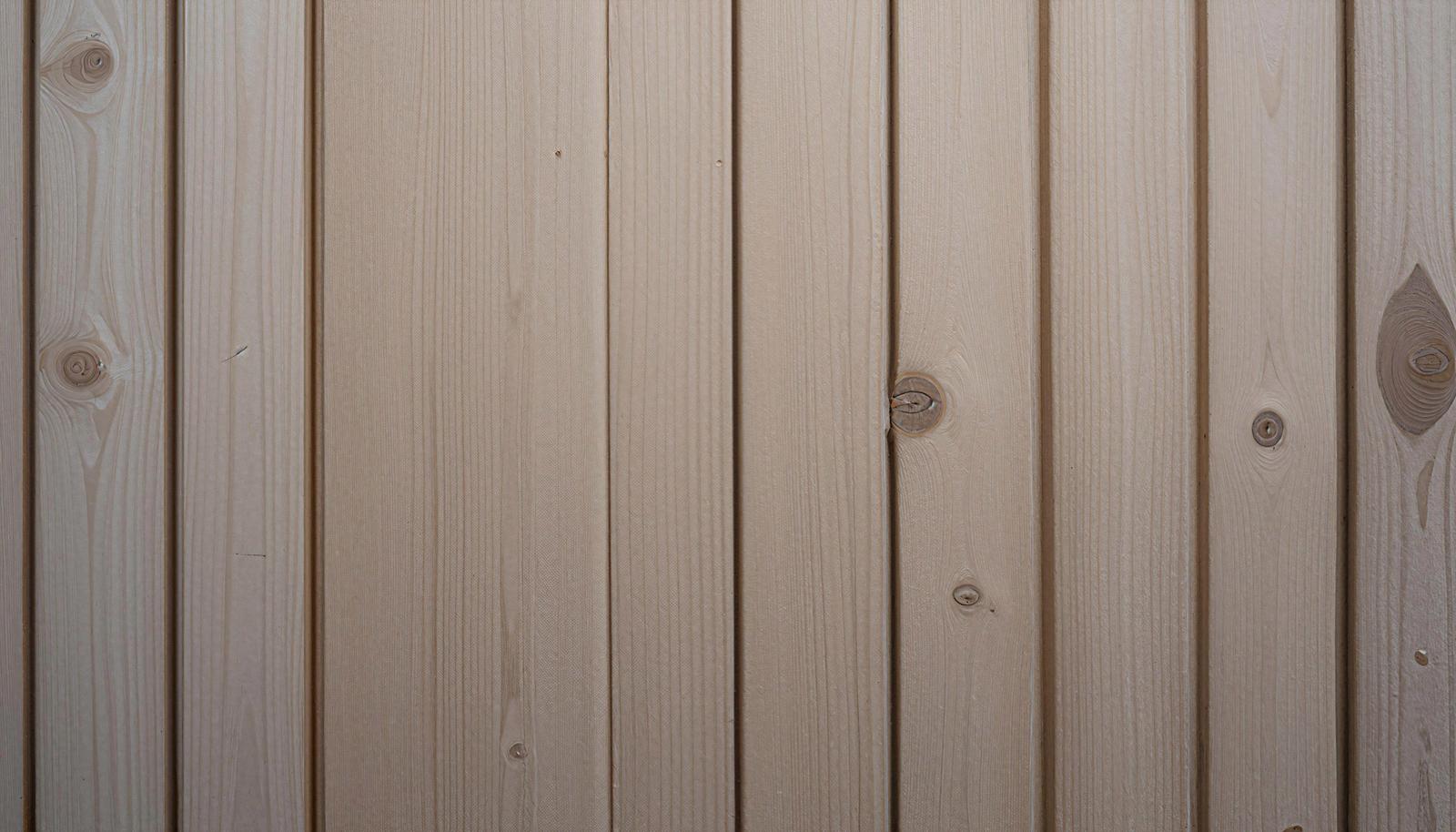 Wall texture with pale wooden boards arranged vertically, showing growth rings and knots
