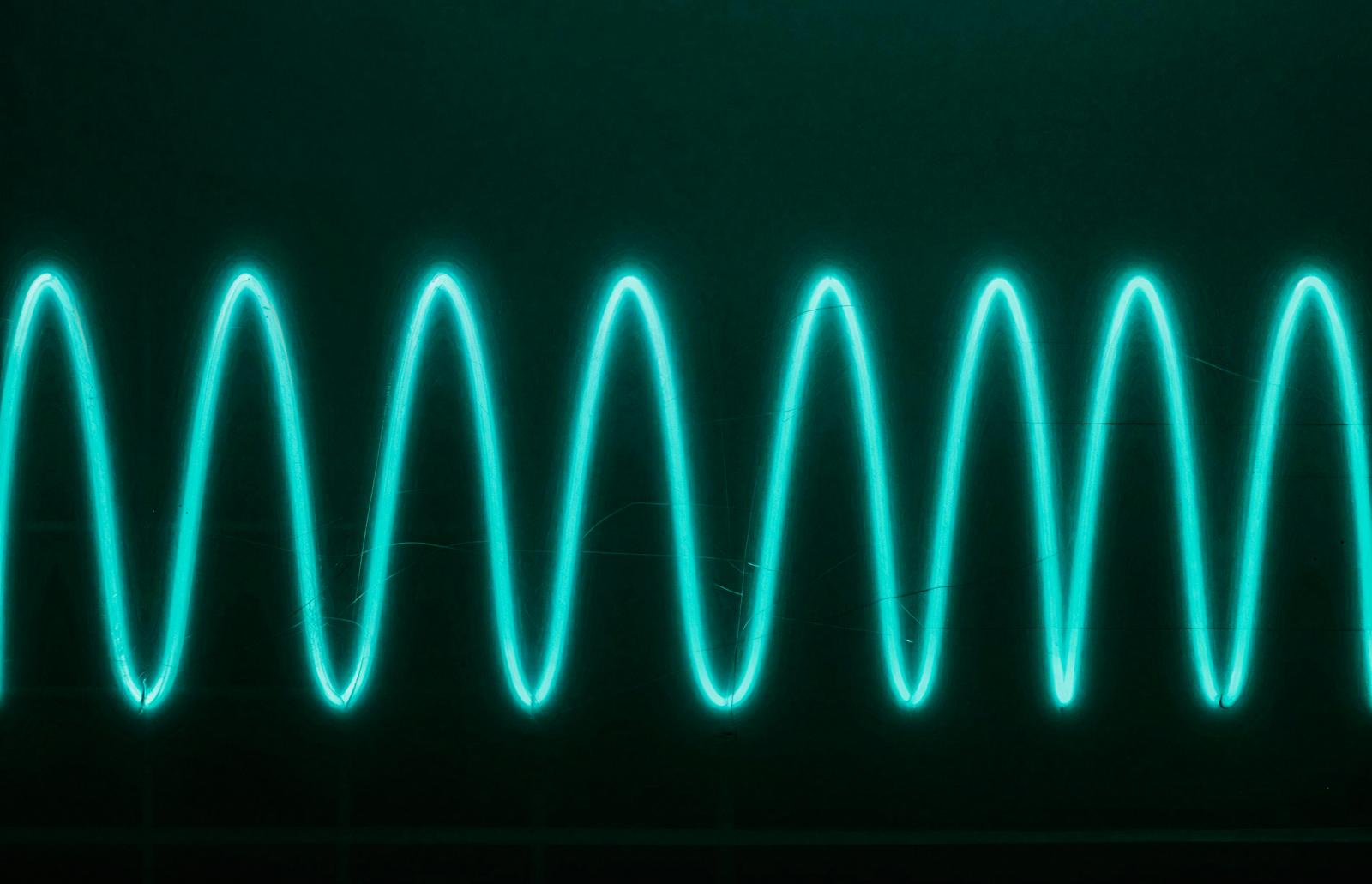 Oscilloscope sine wave glowing in cyan on dark background