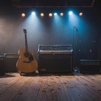 スタジオに置かれたアコースティックギターとアンプ類の写真