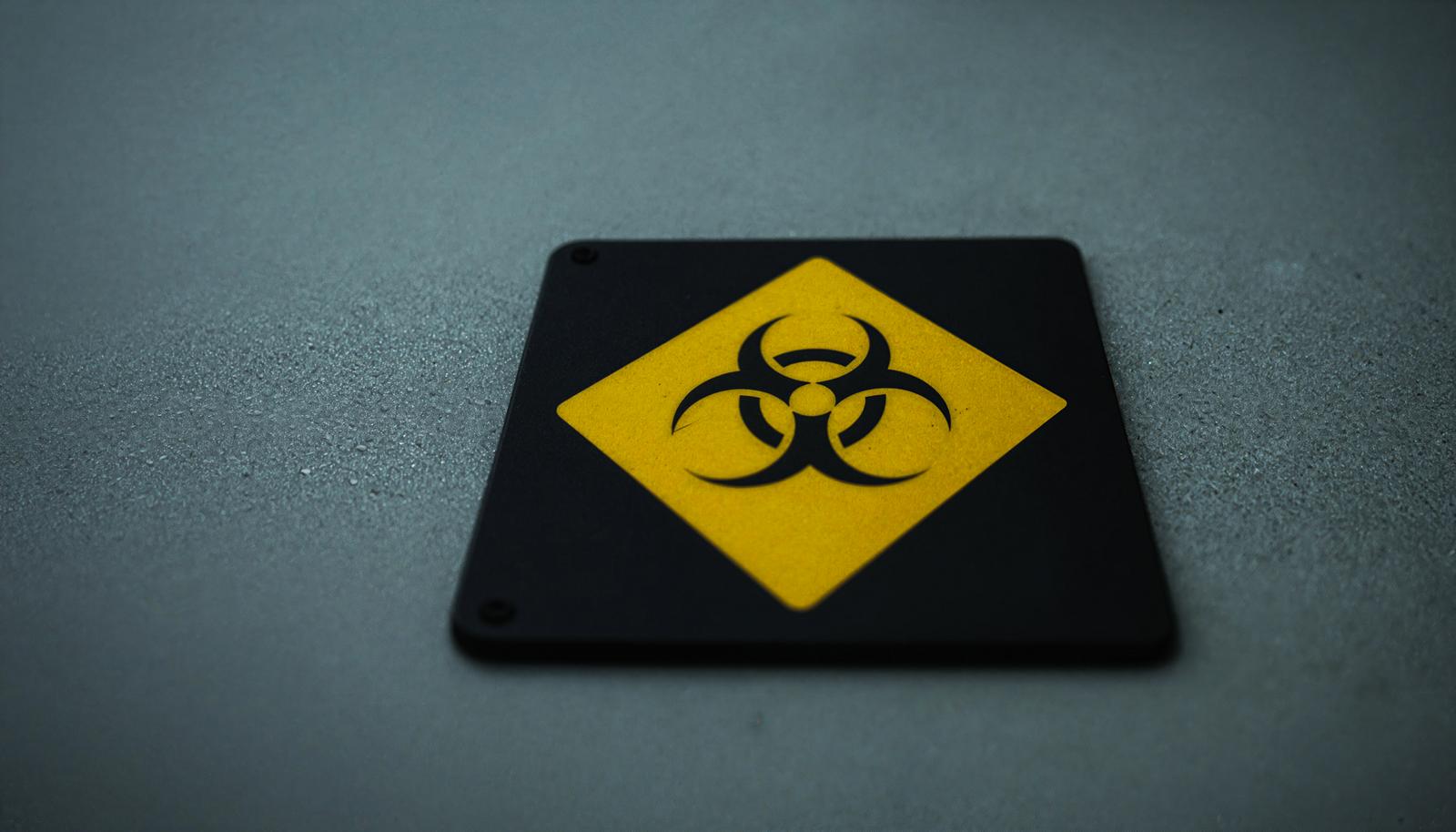 A yellow diamond-shaped warning sign with a black biohazard mark displayed against a black background