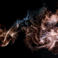 漆黒背景にオレンジと青の煙が立ち上る抽象的デザインの写真