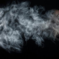 黒背景に白いスモークが流れる煙のエフェクトの写真