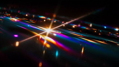 暗闇に放射状に広がる虹色光芒とレンズフレア