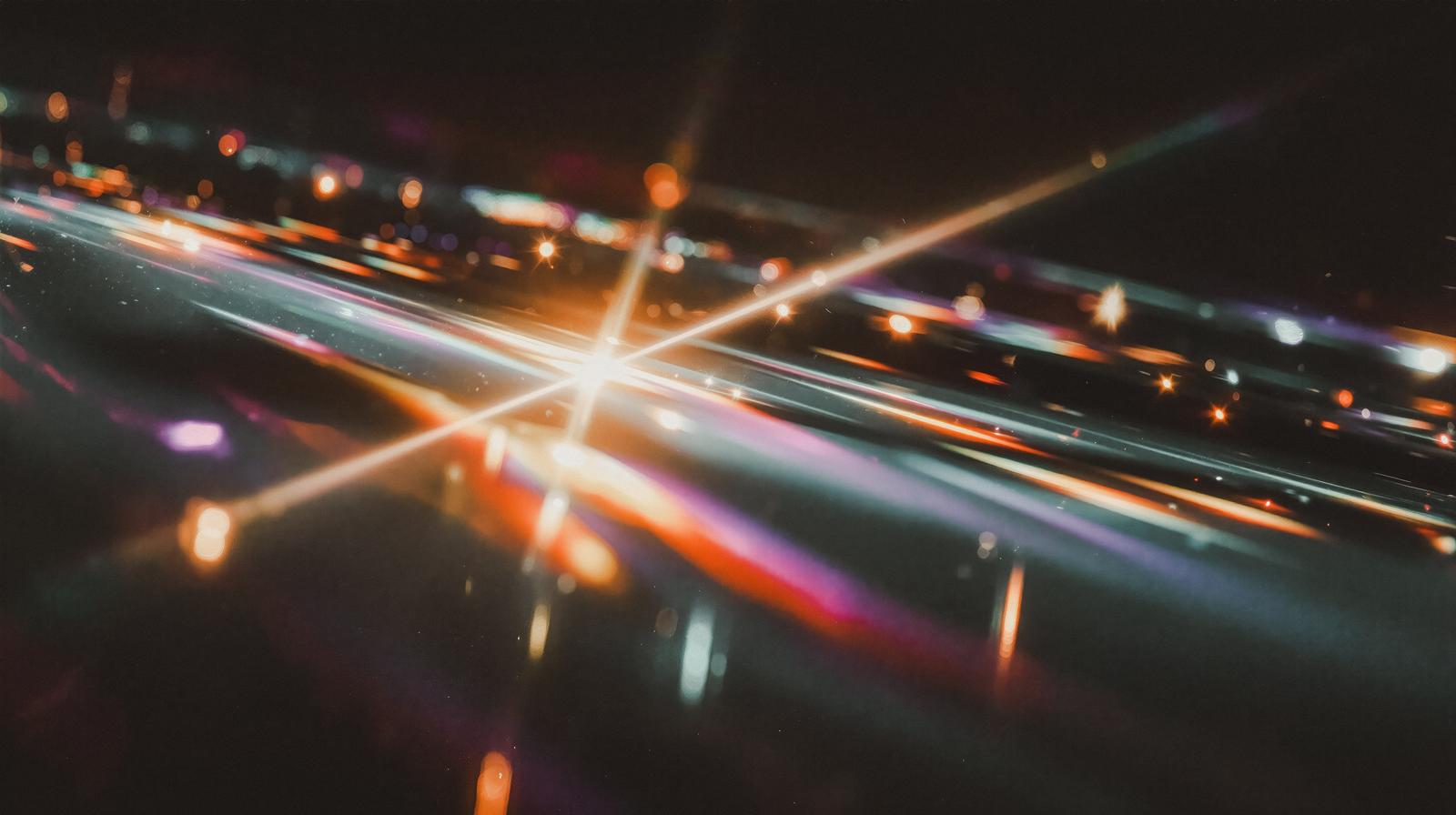 暗い背景に光の束が交差して放射状に伸びるライトトレイル