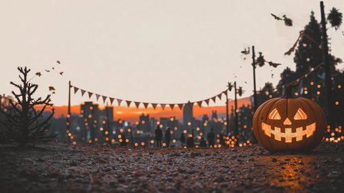 夕焼け空の下で光るパンプキンランタンとガーランドのハロウィン装飾