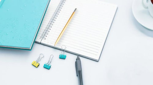 白を基調としたデスクに開かれたノートとペン
