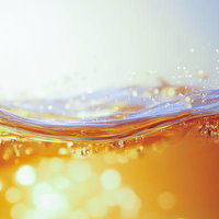 光を浴びた炭酸水の飛沫が生み出す波紋と水しぶきの輝きの写真