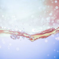 ピンクと青のグラデーション水面に弾ける透明な気泡の写真