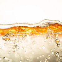 黄金色の液体に舞い上がる透明な気泡と水面の波紋の写真