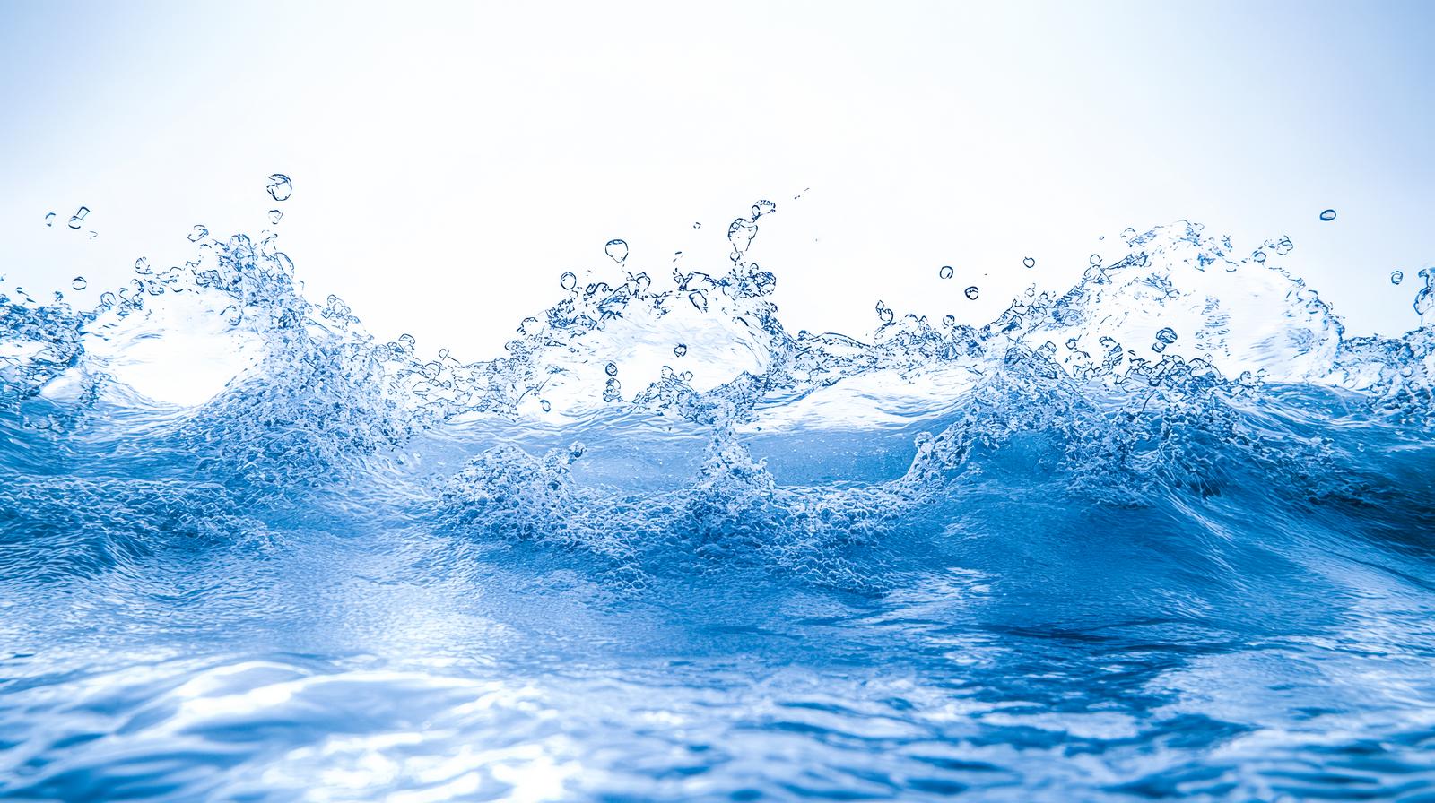 青い波から飛び散る無数の水飛沫が立ち上がる