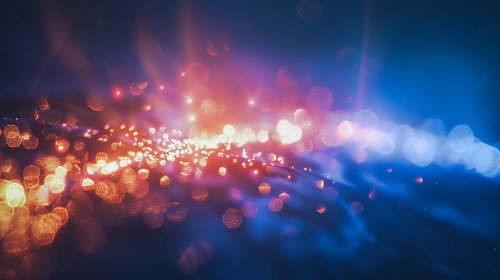 青とオレンジに輝く光の粒が流れる波のグラデーション背景