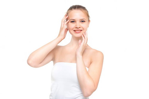 両手を顔に当てながら微笑むスキンケア中の外国人女性