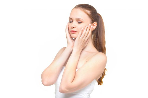 両手を頬に当てながらスキンケアするロシア人美容女性