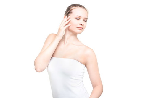 右手を顔の横に添えて視線を逸らす白いチューブトップの女性