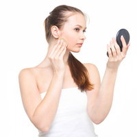 コンパクトミラーを見ながら肌をチェックする女性の写真