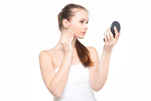 コンパクトミラーを見ながら肌をチェックする女性