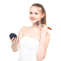 コンパクトミラーを持ちながら首筋にチークブラシを当てる女性の写真