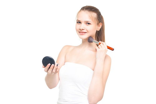 コンパクトミラーを持ちながら首筋にチークブラシを当てる女性