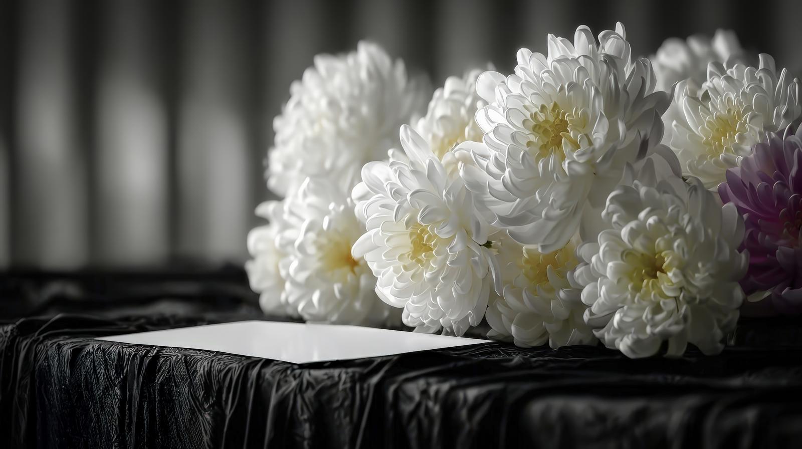 白い菊の花が黒い布の上に並べられた法事用の供花