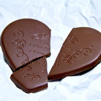 白い紙の上の割れたハートのチョコレートとくしゃくしゃの紙の写真