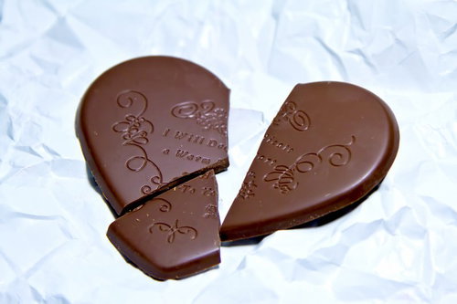 白い紙の上の割れたハートのチョコレートとくしゃくしゃの紙