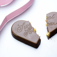 ピンクのリボンが添えられた真っ二つに割れたハートチョコとリボンの写真