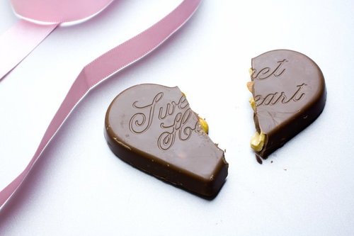 ピンクのリボンが添えられた真っ二つに割れたハートチョコとリボン