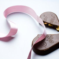 ピンクのリボンの横に並ぶ割れたチョコレートの写真