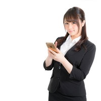 スマホで予定を確認する黒スーツの女性従業員の写真
