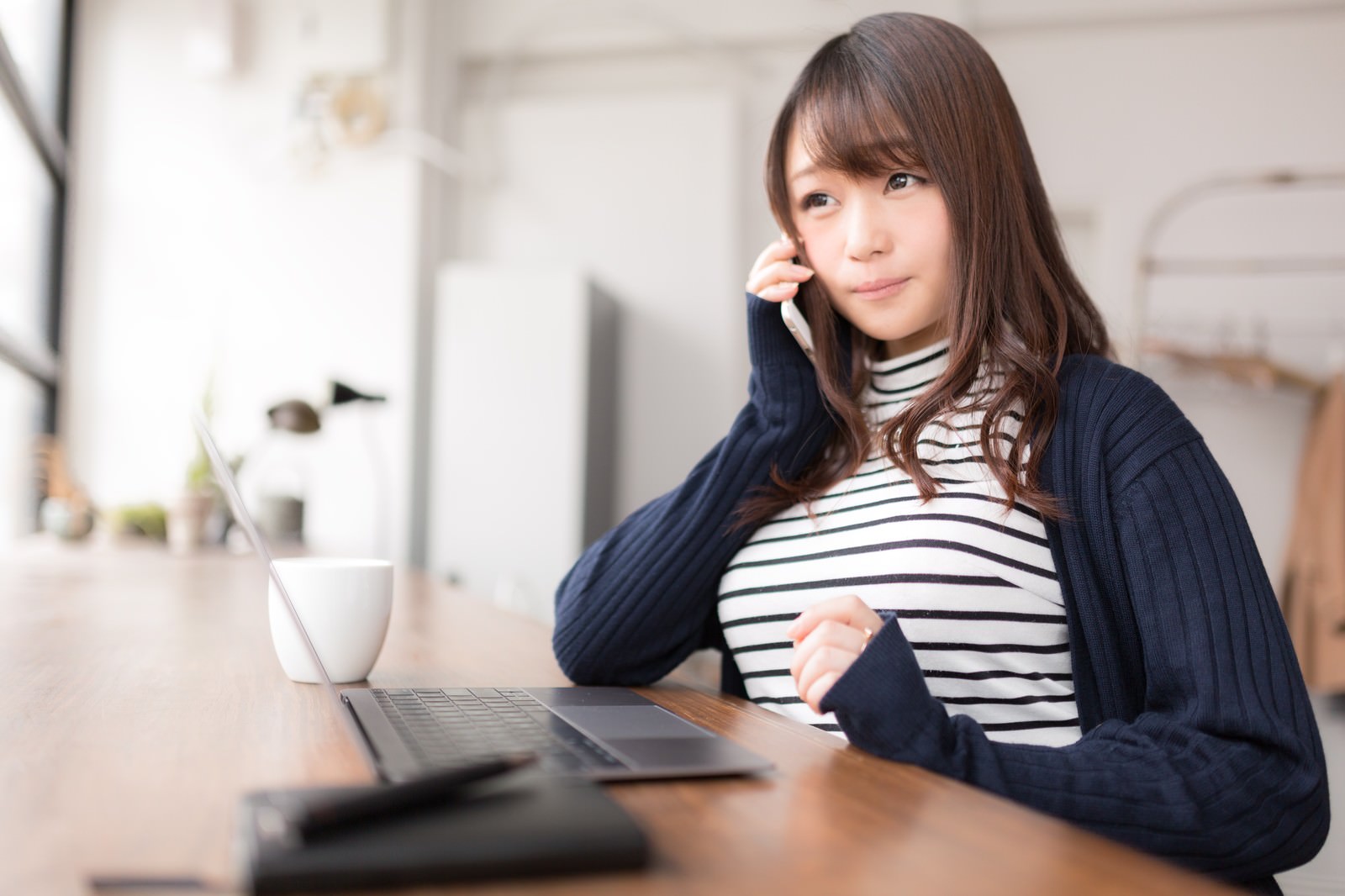 スマートフォンで笑顔で電話するボーダー柄の女性［モデル：茜さや］