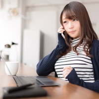 朗報に笑顔が溢れるボーダー柄の服を着た女性がスマートフォンで電話中の写真
