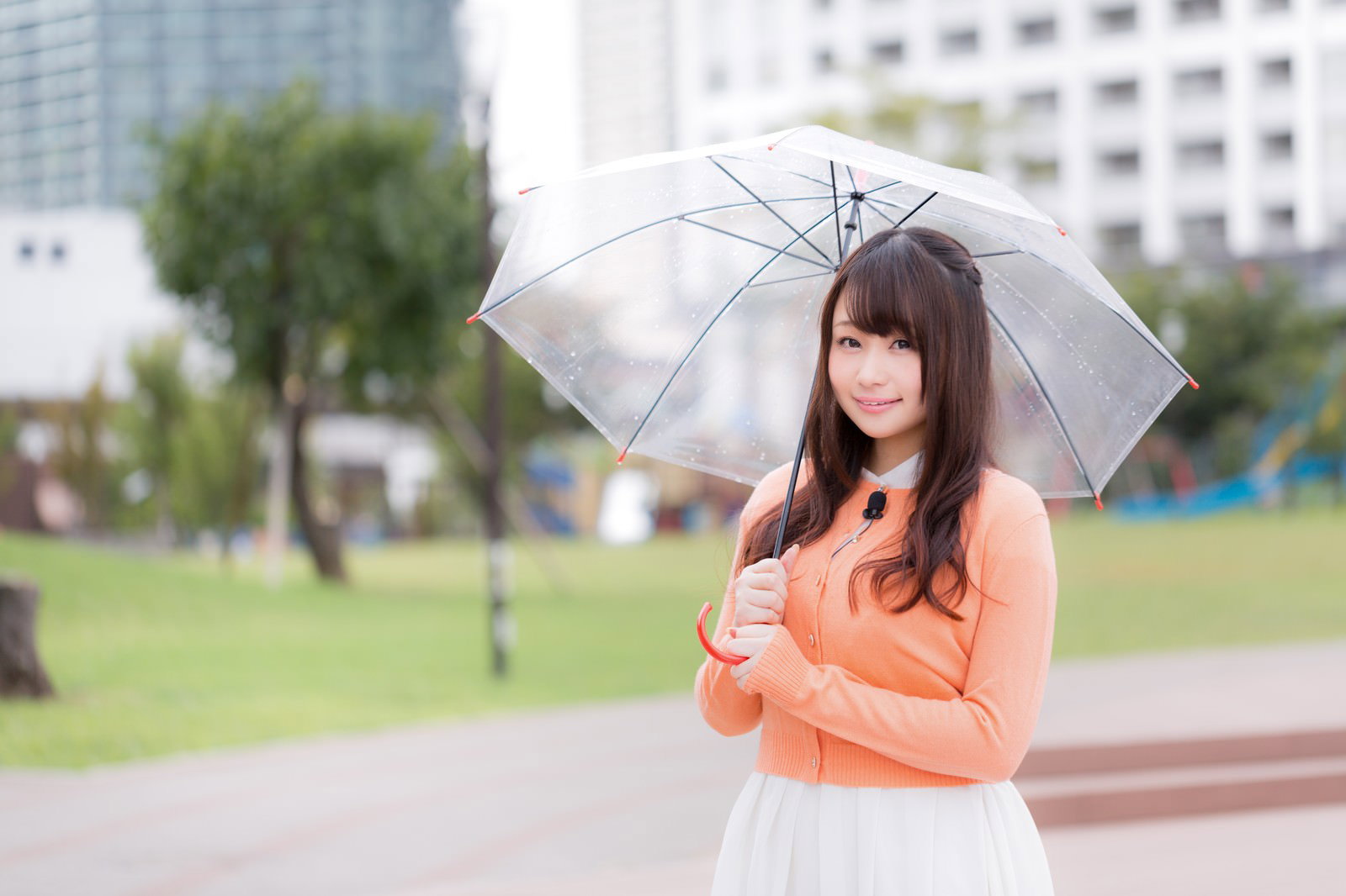 雨の公園で透明傘を持ち笑顔を向ける女性［モデル：茜さや］