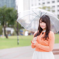 雨の中、透明傘で今日の天気を伝えるお姉さんの写真
