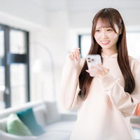 スマホで部屋探しをする笑顔の女性とリラックス空間の写真