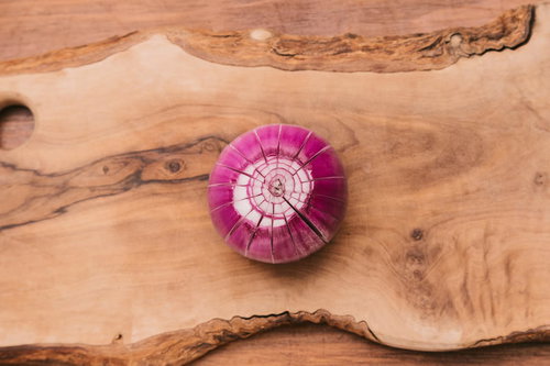 木のまな板の上に置かれた赤玉ねぎをスライスした横断面