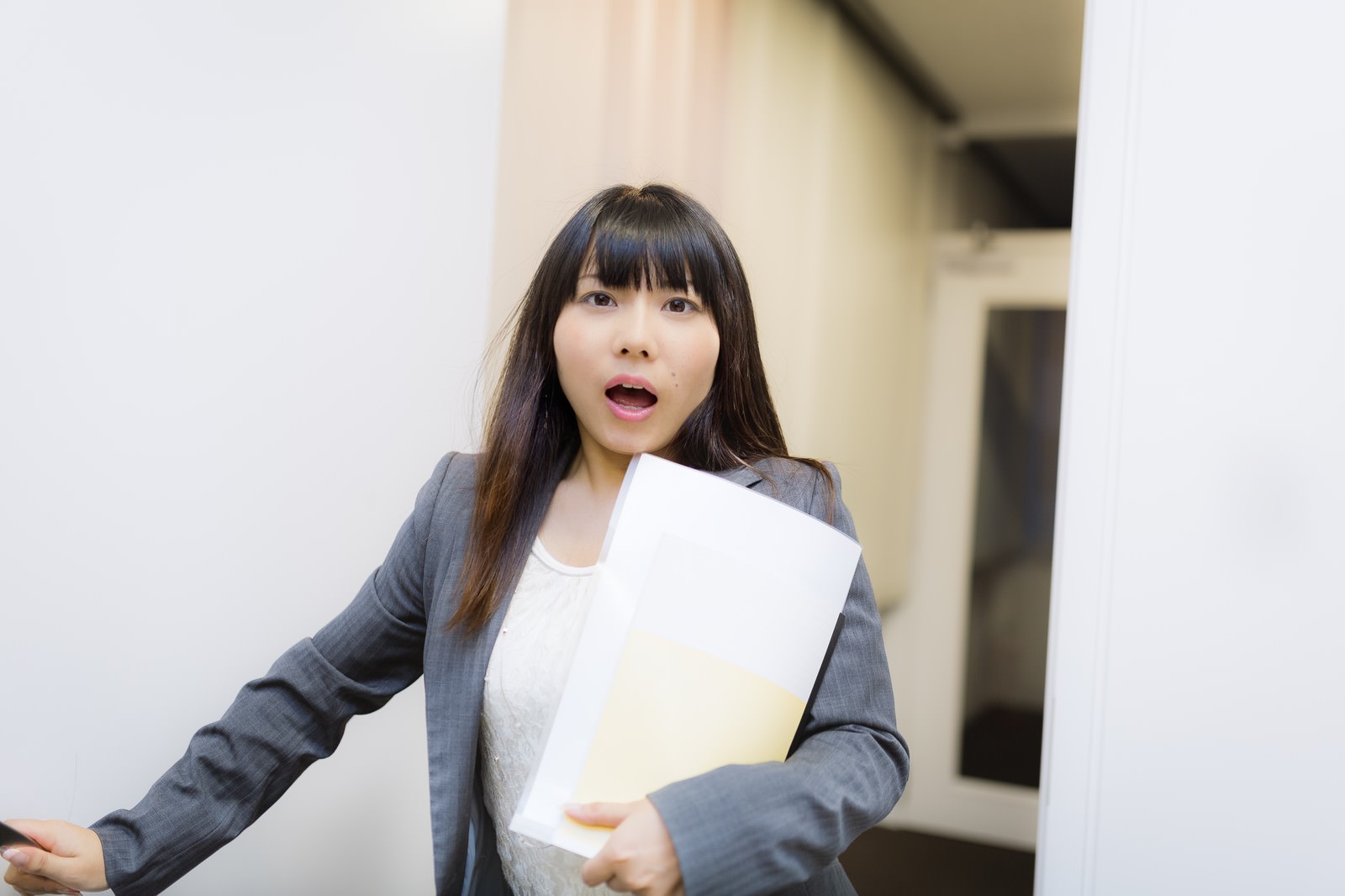 スーツ姿の女性が書類を手に報告する緊急シーン［モデル：Lala］