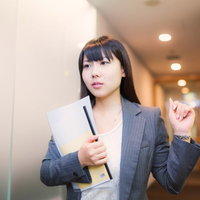 ファイルを持ってオフィスの廊下を歩く女性社員の写真
