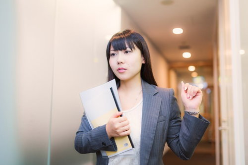 ファイルを持ってオフィスの廊下を歩く女性社員
