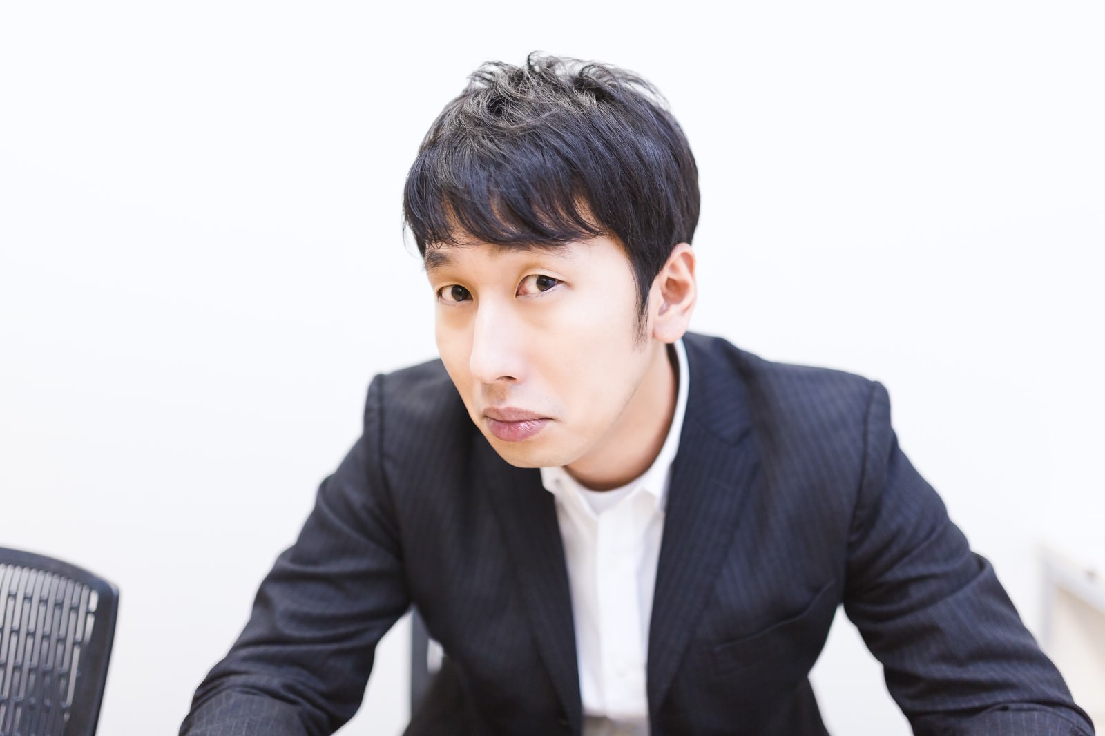 紺色スーツの男性が斜め前を見つめ、自信を持った表情で企画を提案している［モデル：大川竜弥］