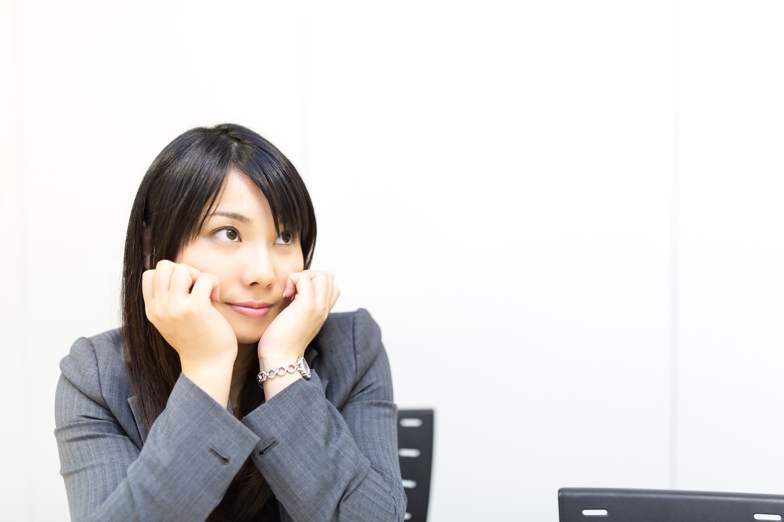 会議中に上目づかいで考える女性社員［モデル：Lala］