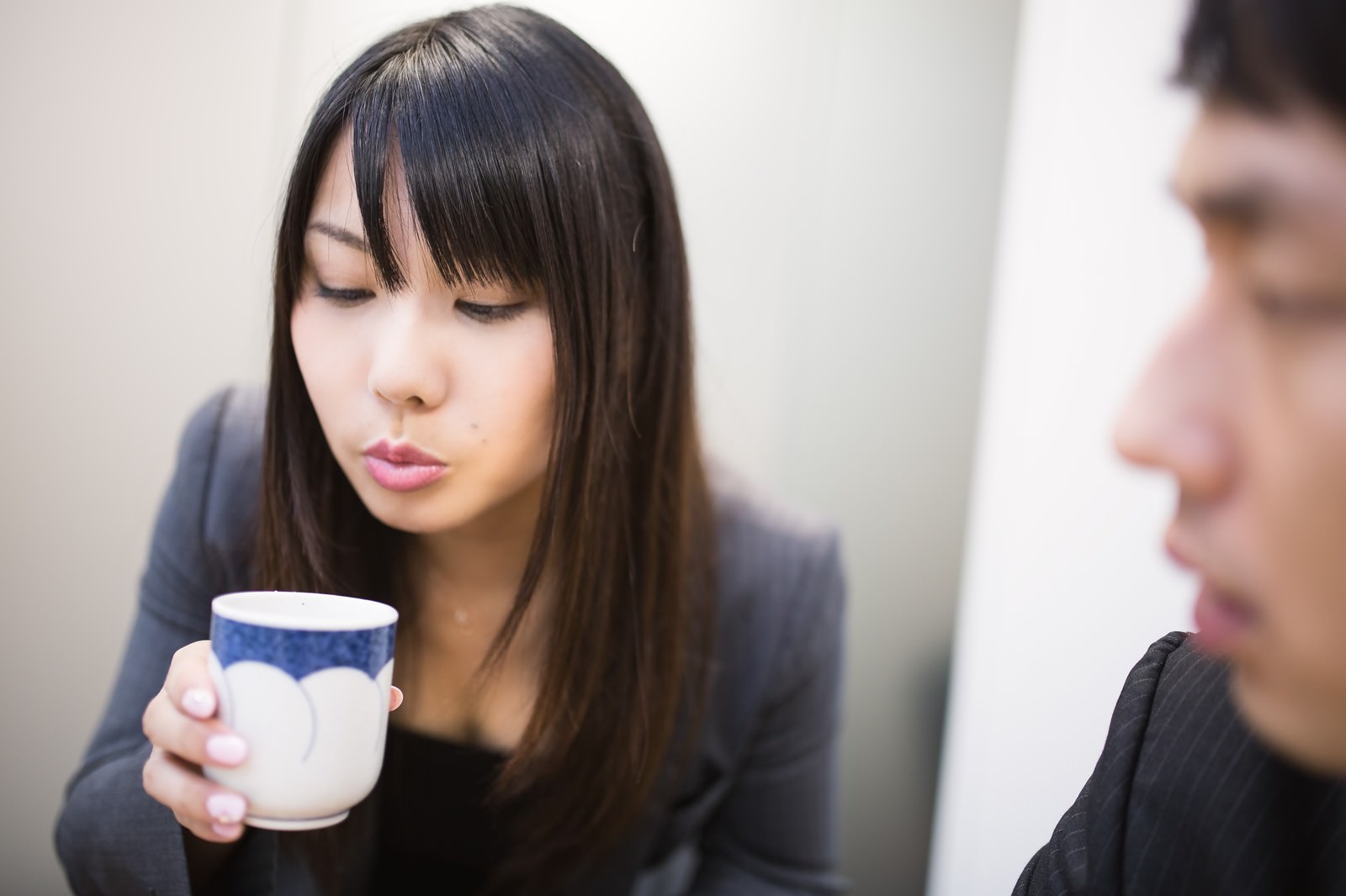 お茶をフーフーして冷ます女性社員［モデル：大川竜弥 Lala］