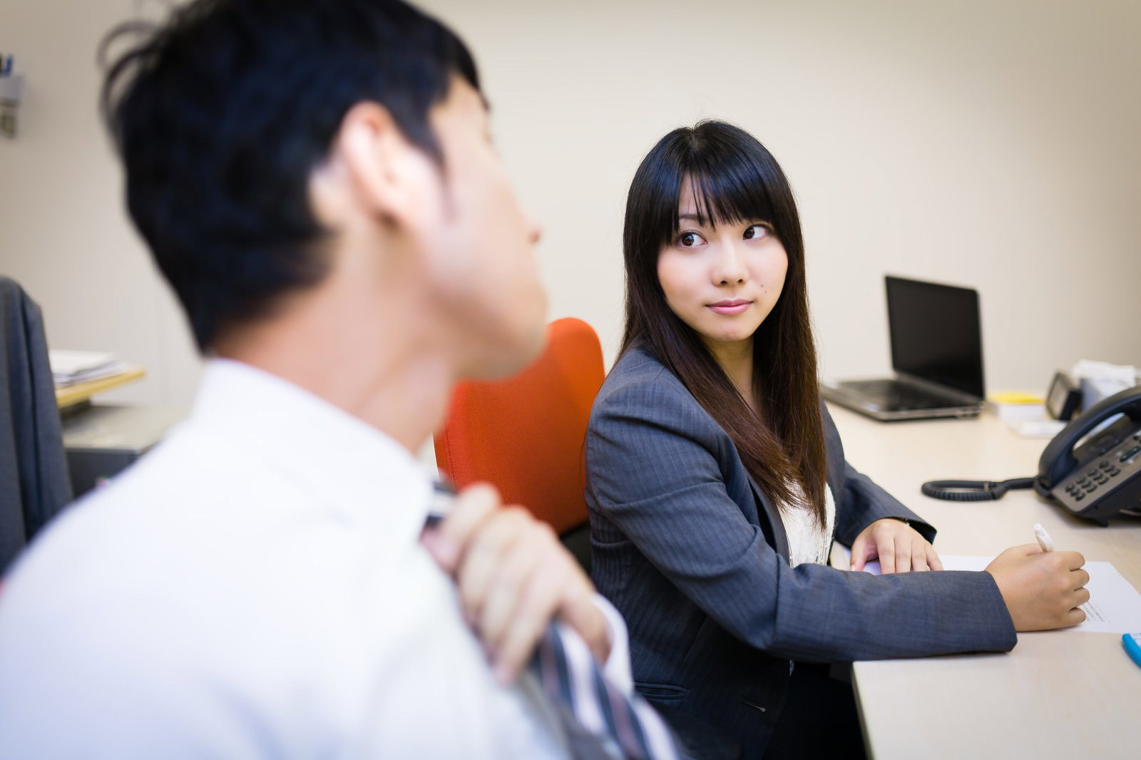 オフィスで男性の横顔を見つめる女性社員［モデル：大川竜弥 Lala］