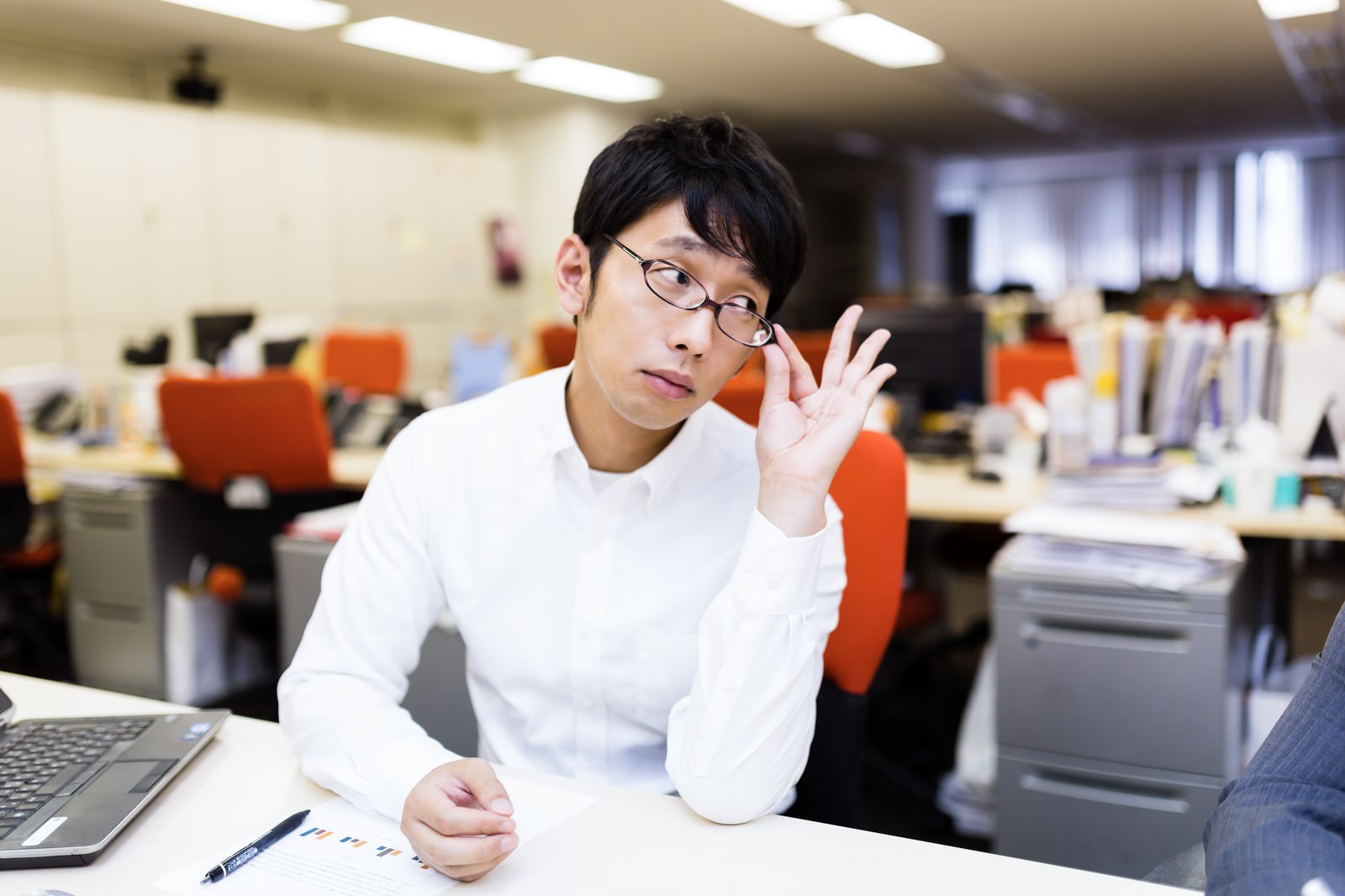 眼鏡を持ち上げ見下ろす男性上司［モデル：大川竜弥］