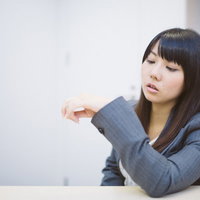 腕に装着したウェアラブルデバイスで時間を気にする女性社員の写真